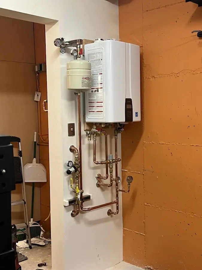 Plumbing technician inspecting water heater connections in Greenhills